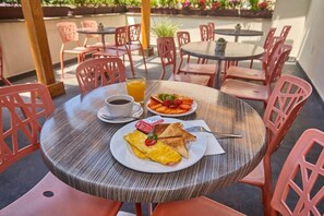 Una mesa redonda con un plato de desayuno, un vaso de jugo de naranja y una taza de café.