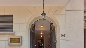 An entrance with a tiled floor, an arched doorway, and a balcony with wrought iron railings. - Senia Reforma (Mexico City)
