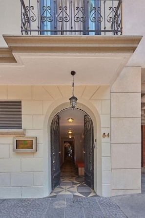Un ingresso con pavimento piastrellato, un arco e un balcone con ringhiere in ferro battuto.