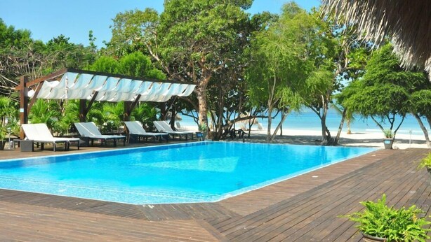 A swimming pool with lounge chairs and a wooden deck.
