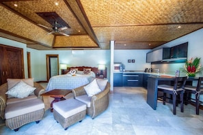 A spacious room with a large bed, two sofas, a dining area, and a kitchen. - Te Manava Luxury Villas Spa (Rarotonga)