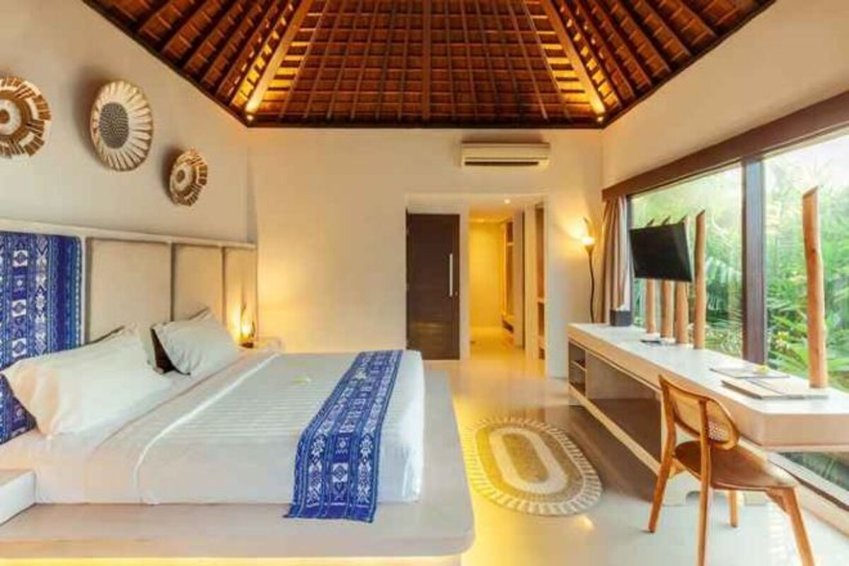 Quarto moderno com uma cama grande, uma escrivaninha e vista para o exterior.