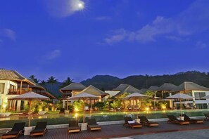 A resort with multiple overwater bungalows, a swimming pool, and lounge chairs.