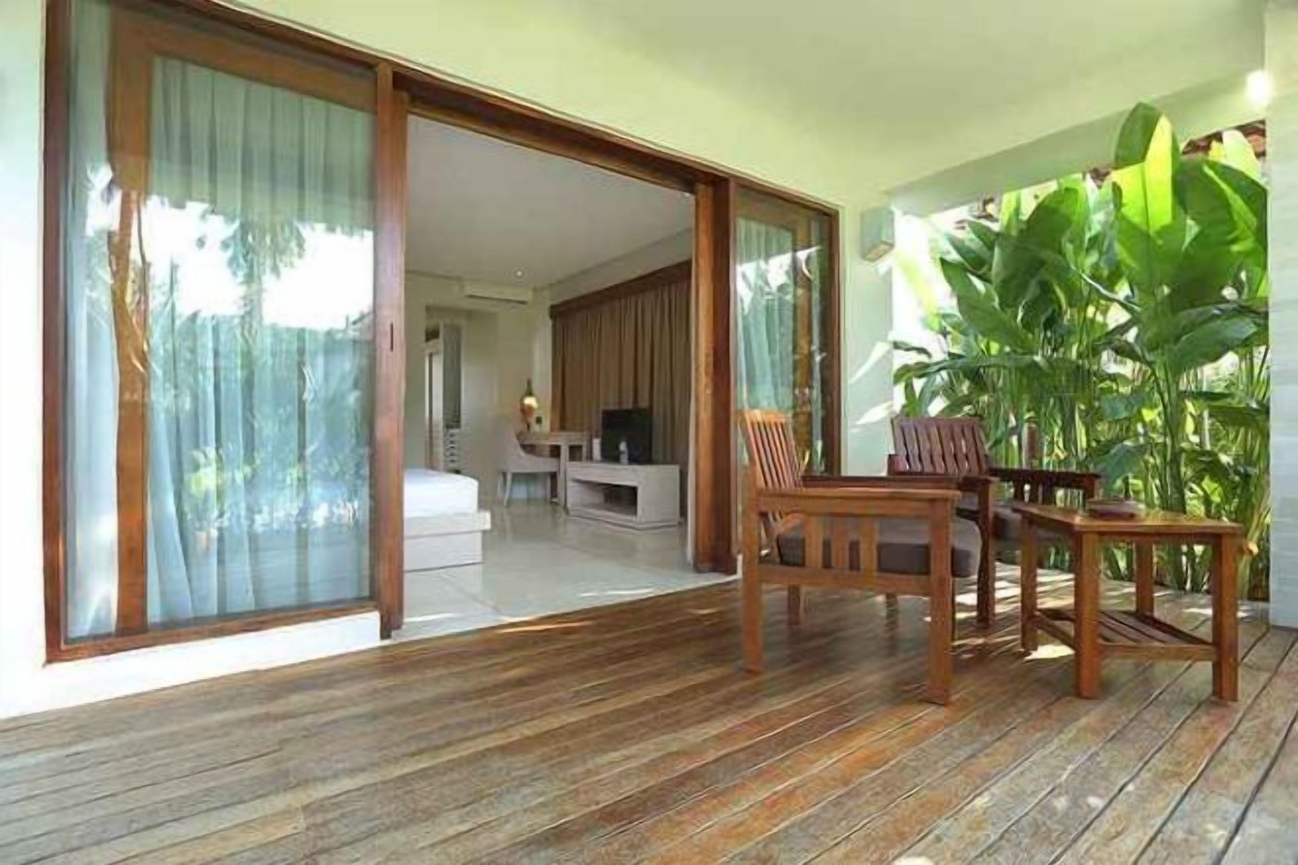 A wooden deck with a dining area and sliding glass doors leading to a bedroom.