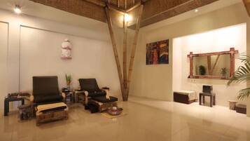 A spacious room with a high ceiling, a large mirror, and a seating area with two chairs and a small table.
