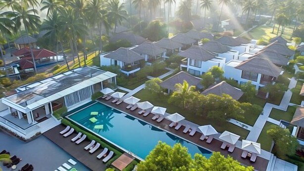 A resort with a swimming pool, lounge chairs, and villas.