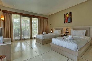 Habitación de hotel con dos camas, un escritorio, una silla, una lámpara y un cuadro en la pared.