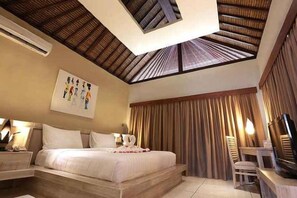 Una habitación de hotel con cama, mesita de noche, lámpara y televisor.