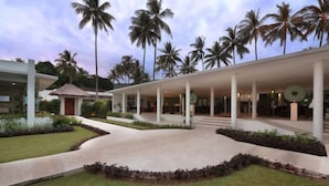 A modern building with a covered walkway, palm trees, and a well-maintained lawn.