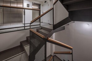 A modern staircase with a metal mesh railing and wooden handrails. - GHT Miratge (Lloret de Mar)