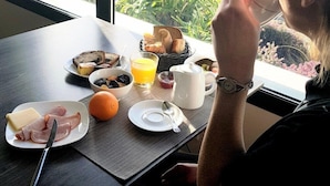 Una mesa de desayuno con platos de comida, un vaso de jugo de naranja y vista al océano.