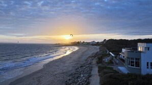 Een strand met een gebouw naast de kust, met een pad dat naar het gebouw leidt.