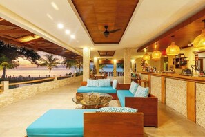 An outdoor lounge area with seating and a bar, overlooking a beach. - Living Asia Resort Spa Lombok (Senggigi)