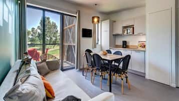 Un interior moderno con sofá, mesa de comedor, sillas y zona de cocina.