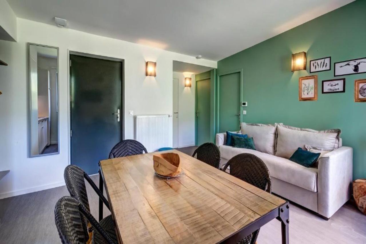 Una habitación con una mesa de comedor, sillas, un sofá y una pared decorada con cuadros.