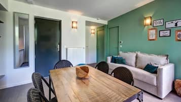 Una habitación con una mesa de comedor, sillas, un sofá y una pared decorada con cuadros.