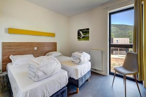 A hotel room with two beds, a window with a view of the outdoors, and a chair. - Le Village des Oiseaux (Motz)