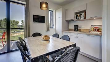 A modern kitchen with a dining area, large windows, and a view of the outdoors.
