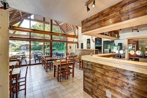 A restaurant with a wooden interior, large windows, and a counter with a menu.