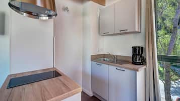 A compact kitchen with a stainless steel range hood, a wooden countertop, a sink, and cabinets.