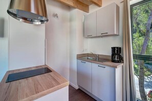 A compact kitchen with a stainless steel range hood, a wooden countertop, a sink, and cabinets. - Le Village des Oiseaux (Motz)