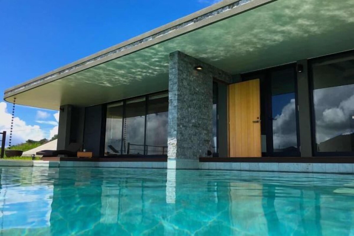 Un edificio moderno con piscina frente a él.