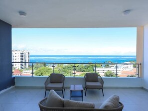 A balcony with a view of the ocean, two chairs, a small table, and a sofa. - Nyali Luxury Apartments  (Mombasa)