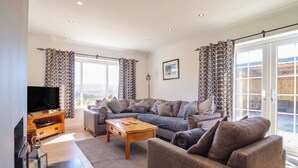 A spacious living room with a large sofa set, a coffee table, and a flat-screen TV. - Tyn Y Weirglodd (Caernarfon)