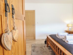 A bedroom with a wooden bed, a nightstand, and a lamp. - Tyn Y Weirglodd (Caernarfon)
