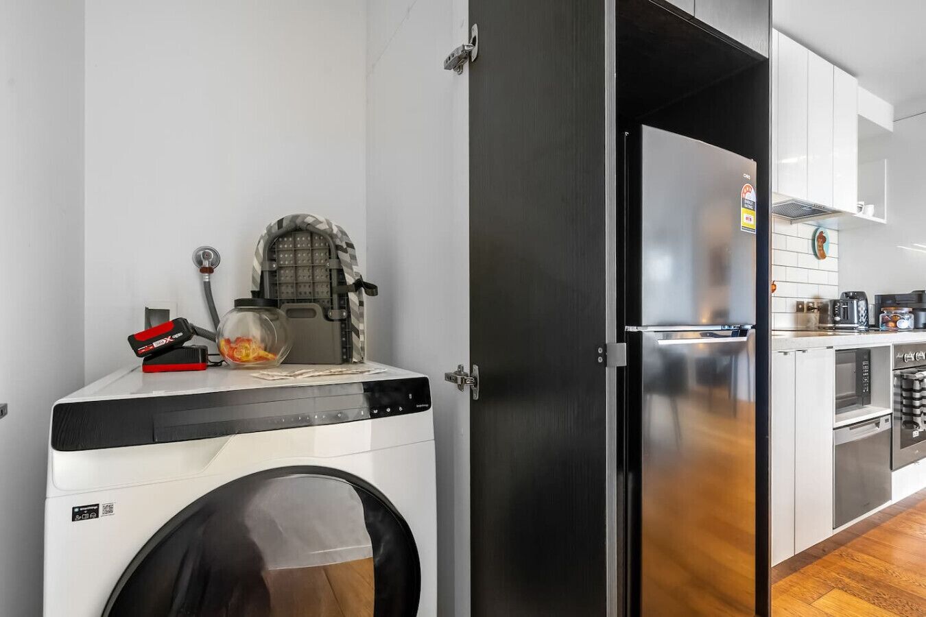 A compact kitchen with a built-in washing machine, a compact refrigerator, and a microwave.