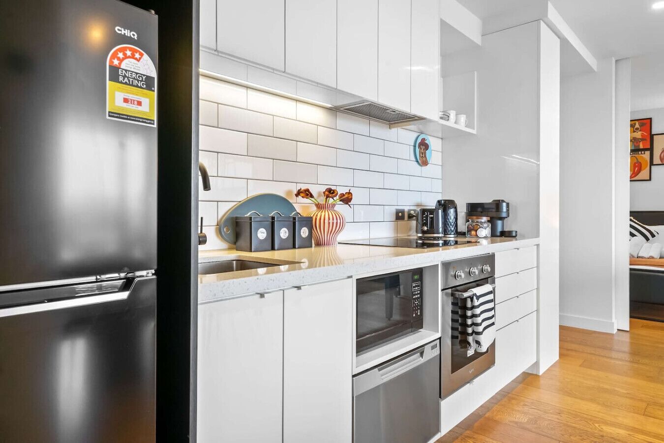 A modern kitchen with a stainless steel refrigerator, white cabinetry, a tiled backsplash, and a wooden countertop.
