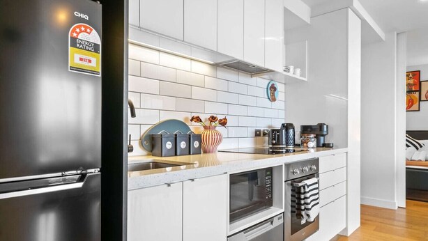 Eine moderne Küche mit Edelstahlkühlschrank, weißen Schränken, einer gefliesten Spritzschutzwand und einer Holzarbeitsplatte.