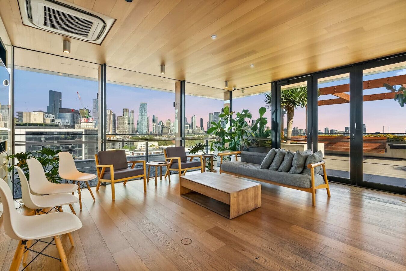 A modern interior with a city view, wooden flooring, and a mix of seating arrangements.