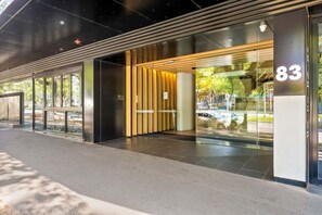 A modern building entrance with a glass facade, a numbered sign, and a metal railing. - Walk to Melbourne Uni | Foosball & Free Parking (North Melbourne)