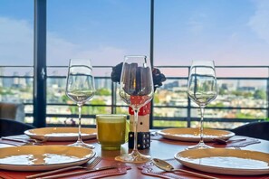 A table set for dining with wine glasses, plates, and cutlery, overlooking a cityscape. - Walk to Melbourne Uni | Foosball & Free Parking (North Melbourne)
