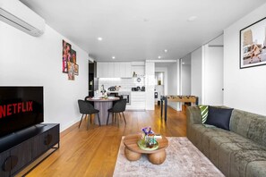 Ein modernes Wohnzimmer mit Flachbildfernseher, rundem Couchtisch und einer Couch.