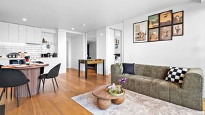 Ein modernes Wohnzimmer mit Küche, Essbereich und einer Couch mit kariertem Kissen.