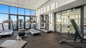 Une salle de sport équipée de tapis de course, d’un rameur et d’un banc de musculation.