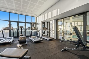 Ein Fitnessraum mit Laufbändern, Rudergerät und einer Bank.
