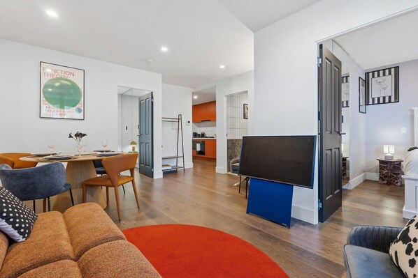 A modern living space with a dining area, a TV, and a kitchen in the background. - CBD Apt Near Queen Vic Market, Hospital & Trams (Melbourne)