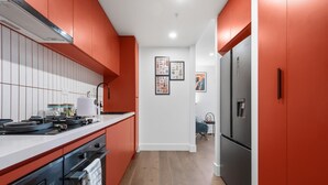 Une cuisine moderne avec des meubles de rangement rouges, un réfrigérateur en acier inoxydable et un plancher en bois.