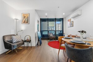 A modern living room with a sofa, armchair, and dining table set. - CBD Apt Near Queen Vic Market, Hospital & Trams (Melbourne)