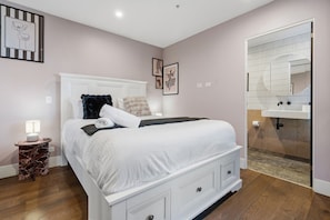A bedroom with a bed, bedside table, and a bathroom with a sink and mirror. - CBD Apt Near Queen Vic Market, Hospital & Trams (Melbourne)