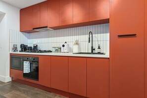 Een moderne keuken met een inbouwoven, een gasfornuis en een roestvrijstalen spoelbak.