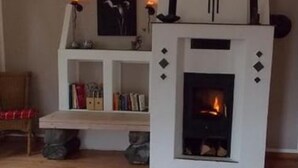 A living room with a fireplace, a bookshelf, and a framed picture on the wall.