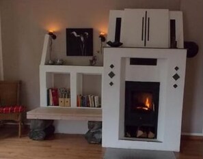 A living room with a fireplace, a bookshelf, and a framed picture on the wall.