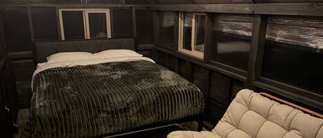 A bedroom with a bed, a sofa, and a window.