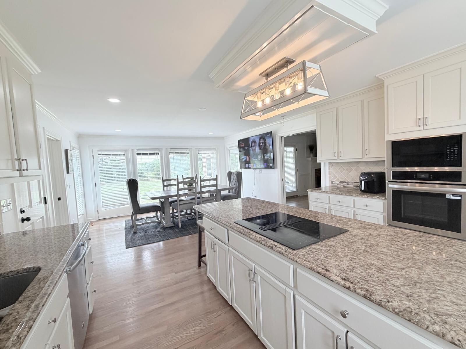 A modern kitchen with white cabinetry, a granite countertop, and stainless steel appliances.