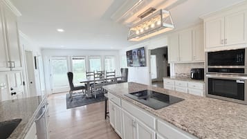 A modern kitchen with white cabinetry, a granite countertop, and stainless steel appliances.