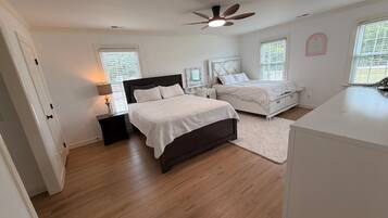 A bedroom with two beds, a ceiling fan, and a large window.